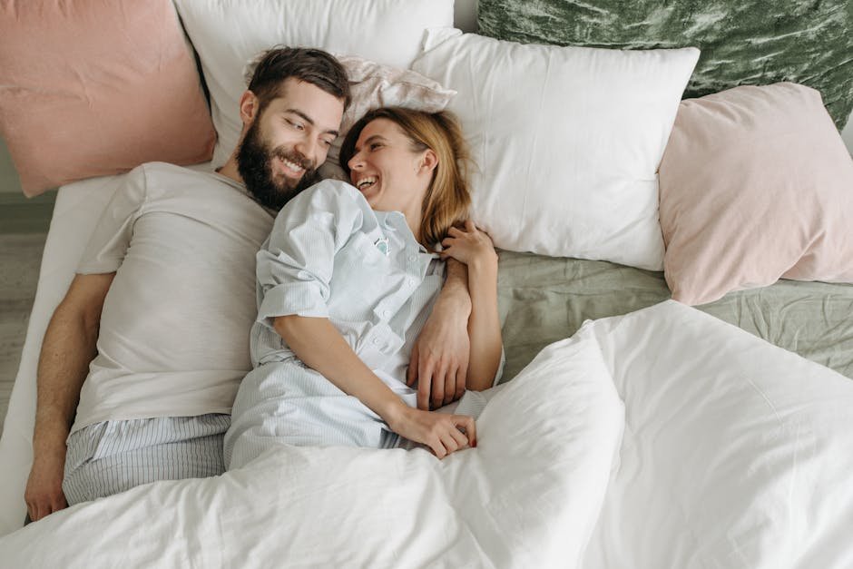 A joyful couple laughing in bed, creating a warm and loving atmosphere at home.