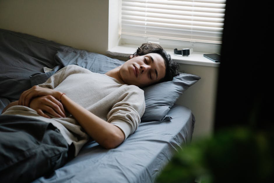 A man calmly sleeps on a bed in a cozy bedroom with soft lighting.