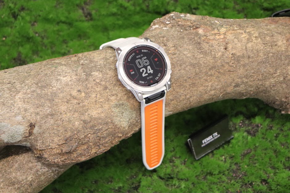 Smartwatch with orange strap placed on a log outdoors, showcasing time and health features.