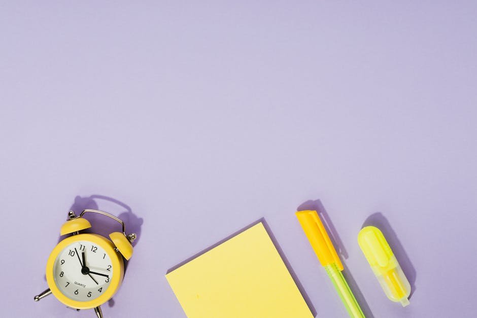 Vibrant desk setup with a yellow alarm clock, sticky notes, and stationery on a purple background.