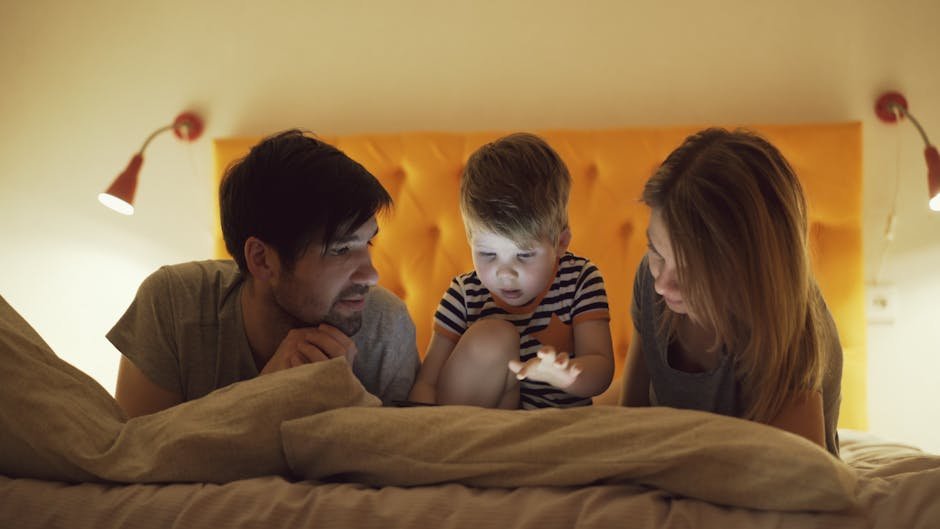 Parents and child enjoying a cozy bedtime moment together with a digital tablet.